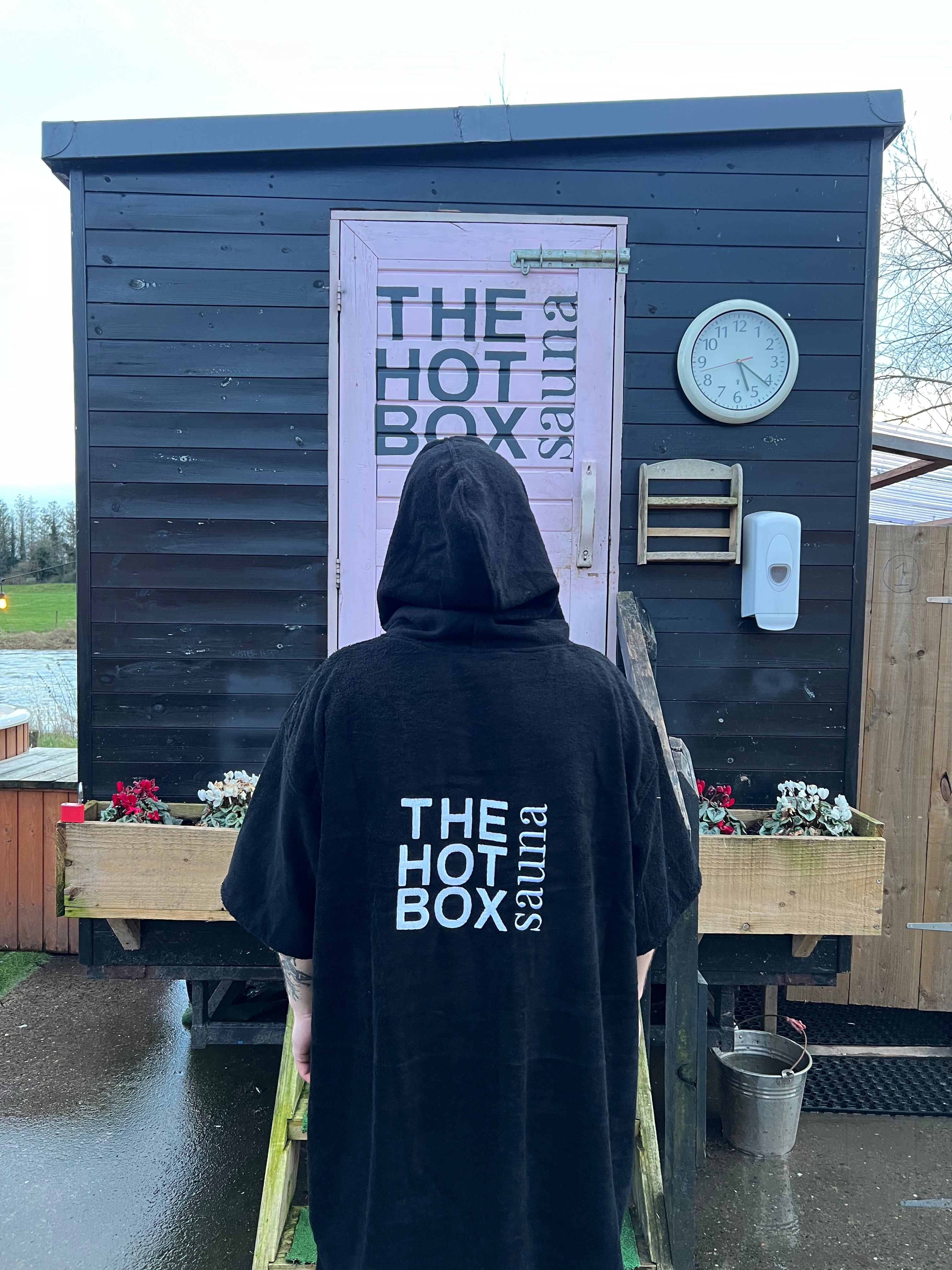 Back of black cotton towelie, showing 'The Hot Box Sauna' logo